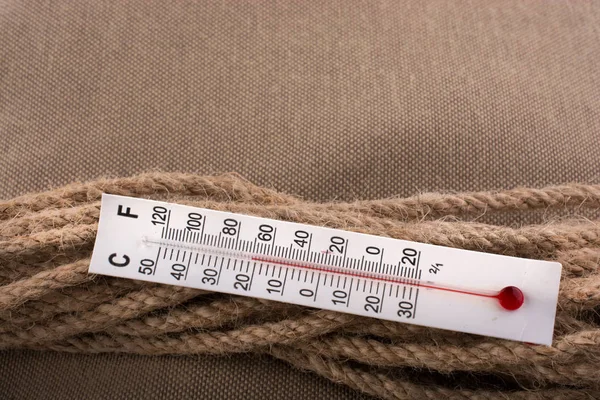 布の背景に茶色のロープ上の温度計 — ストック写真