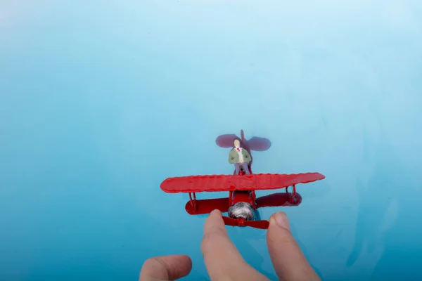 Repülőmodell és egy férfi szobrocska, a víz — Stock Fotó