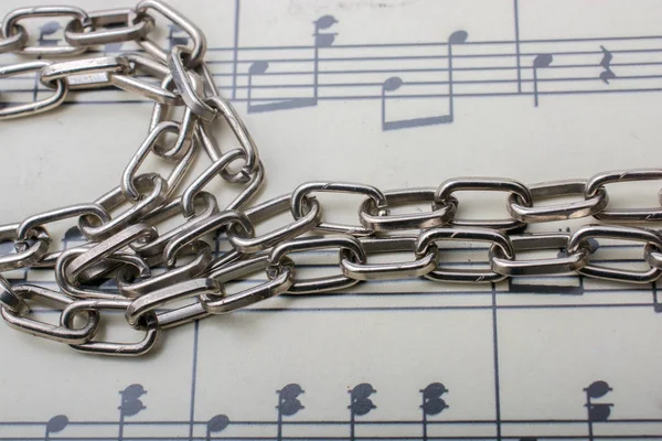 Metal chain placed on paper with musical notes