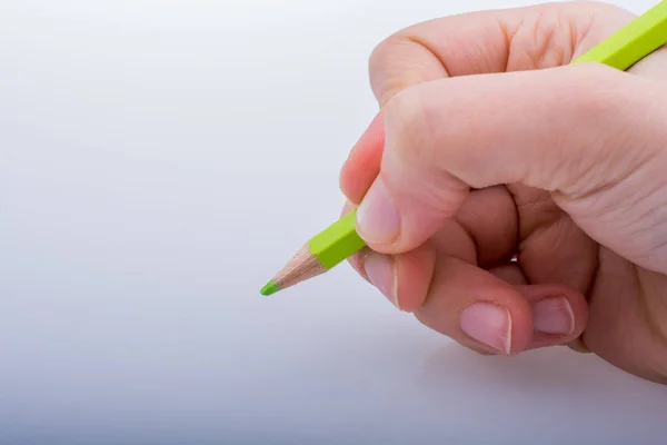 Mano sosteniendo un lápiz de color verde — Foto de Stock