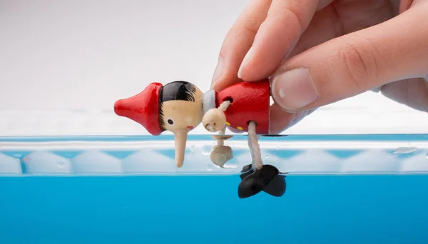 Hand hält Pinocchio im Wasser — Stockfoto