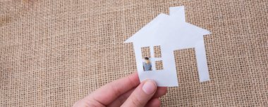 Kağıt ev ve erkek heykeli keten branda arka planda