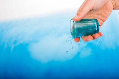 Mavi su üzerinde elinde mavi renk cam 