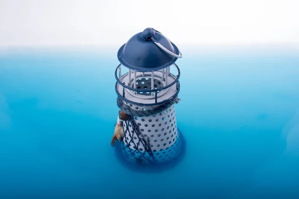 青い水に置かれた小さなモデル灯台 — ストック写真