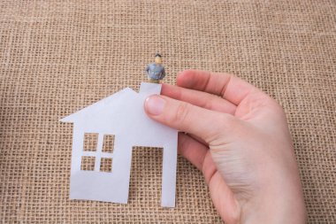 Kağıt ev ve tuval arka plan üzerinde bir adam heykelcik