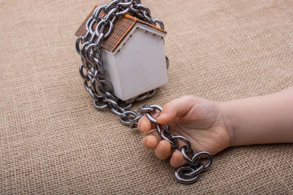 Kis kezében egy lánc egy modell ház körül — Stock Fotó