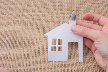 Kağıt ev ve tuval arka plan üzerinde bir adam heykelcik