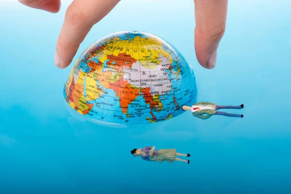 Little globe with    floating figurines around — Stock Photo, Image