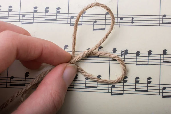 Linen thread placed on paper with musical notes — Stock Photo, Image