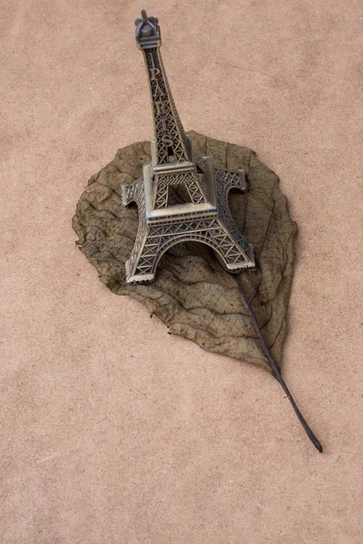 Petit modèle Tour Eiffel et une feuille sèche — Photo