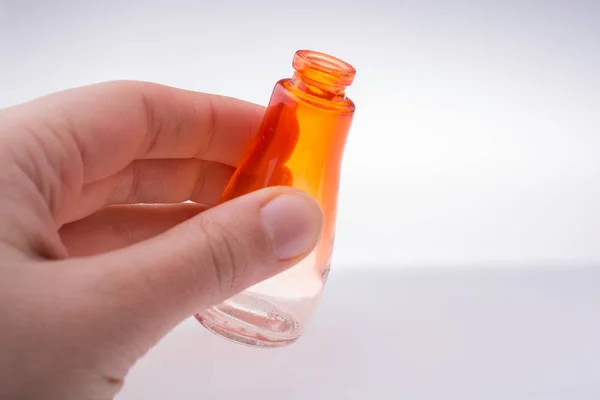Pequeña botella de vidrio vacía de colores en la mano —  Fotos de Stock