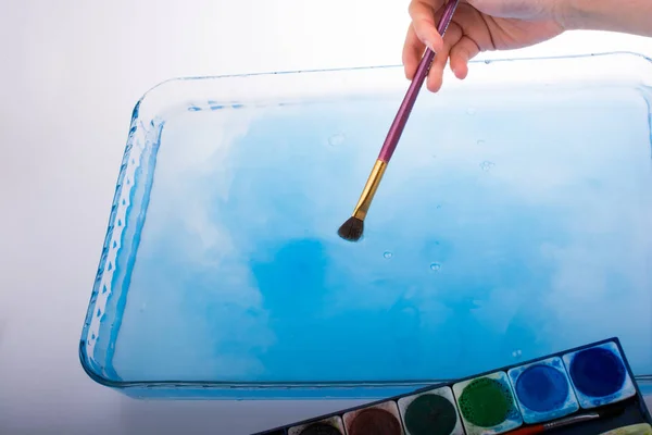 Pintura disolviéndose como pincel de pintura toca el agua —  Fotos de Stock