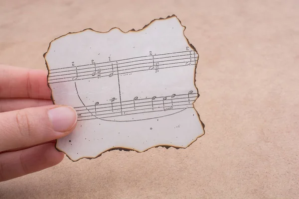 Musical notes on burnt paper in hand — Stock Photo, Image