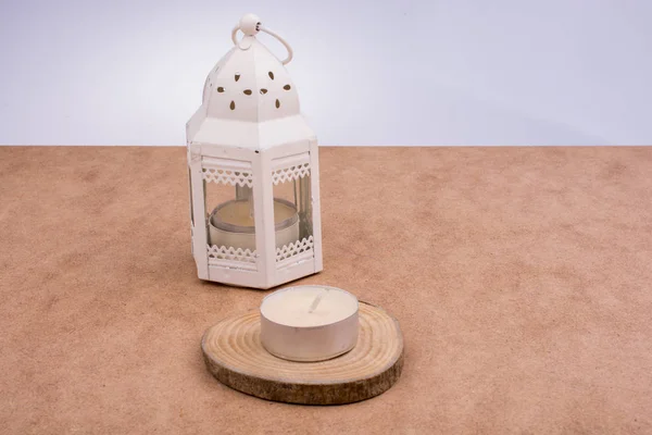 Vela colocada sobre un fondo blanco junto a una lámpara — Foto de Stock