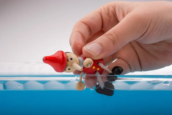 Ruka držící Pinocchio ve vodě — Stock fotografie