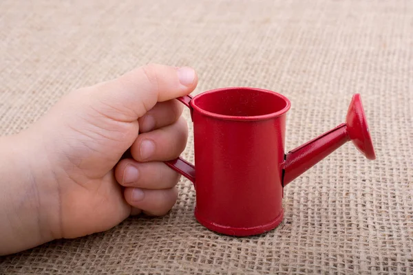 Hand holding a watering can on  canvas background