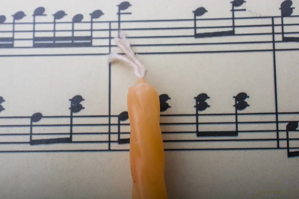 Vela colocada sobre papel con notas musicales — Foto de Stock