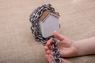 Küçük el modeli evin etrafında bir zinciri tutarak 