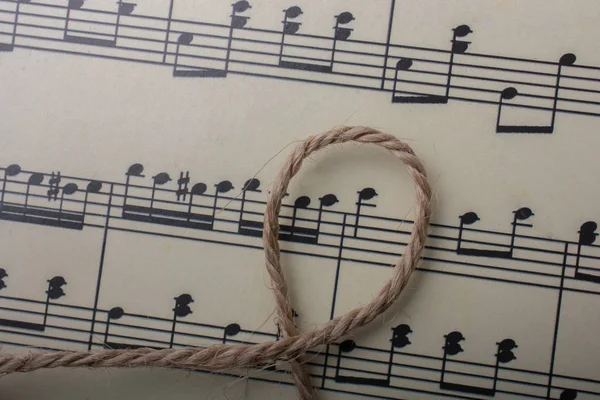 Linen thread placed on paper with musical notes — Stock Photo, Image