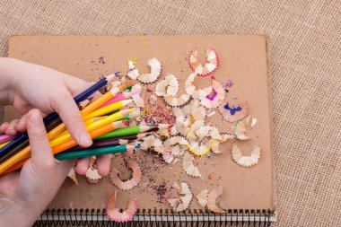 Renkli kalemler üzerinde bir defter tutan el