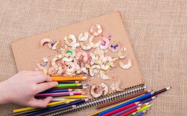 Renkli kalemler üzerinde bir defter tutan el