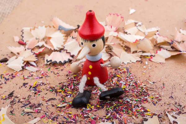 Pinocchio sedící uprostřed tužkou hobliny — Stock fotografie