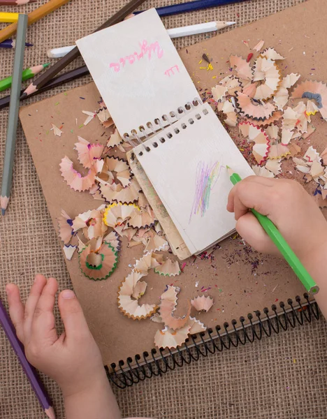 Spiral defter üzerinde bir renk kalem tutan el 