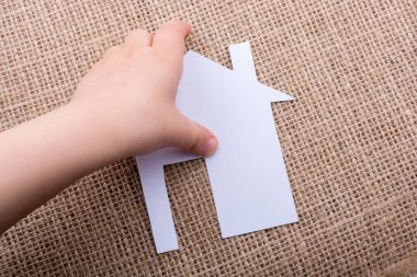 Tuval üzerinde bir kağıt ev tutan el 