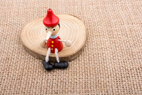 Pinokio lalka siedzi na drewno na płótnie — Zdjęcie stockowe