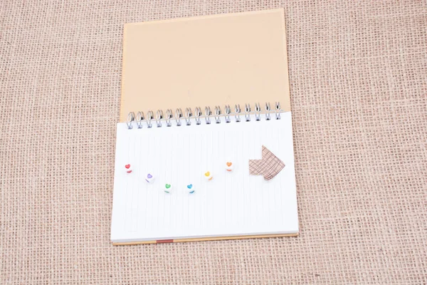 Cubos de amor y flecha de papel en un cuaderno — Foto de Stock