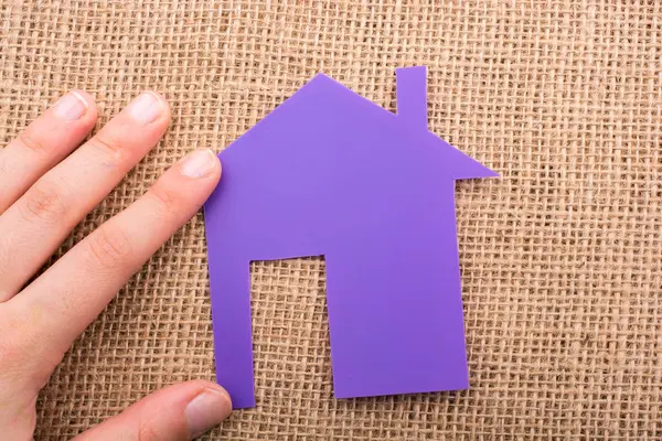 Tuval üzerinde bir kağıt ev tutan el 