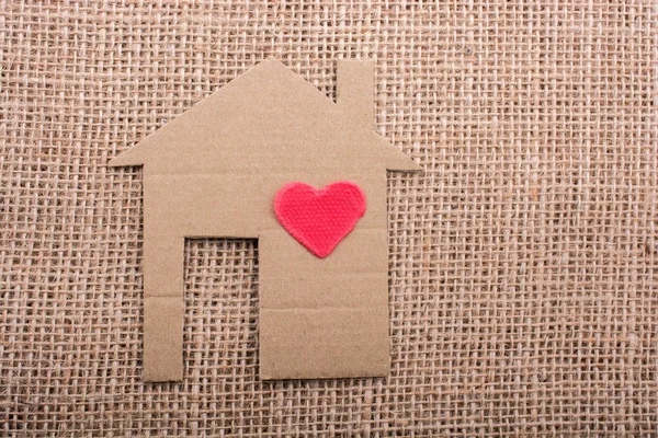 Форма сердца на форме дома вырезанная из бумаги — стоковое фото