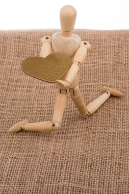 Tahta bir oyuncağın elinde kalp şeklinde bir nesne