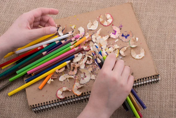 Renkli kalemler üzerinde bir defter tutan el