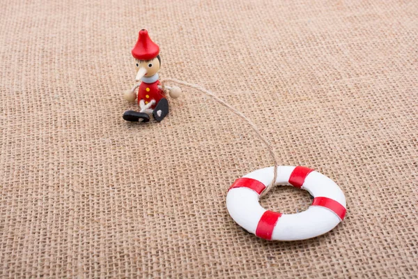 Pinokyo bebeği tuvaldeki can yeleğine bağlı.