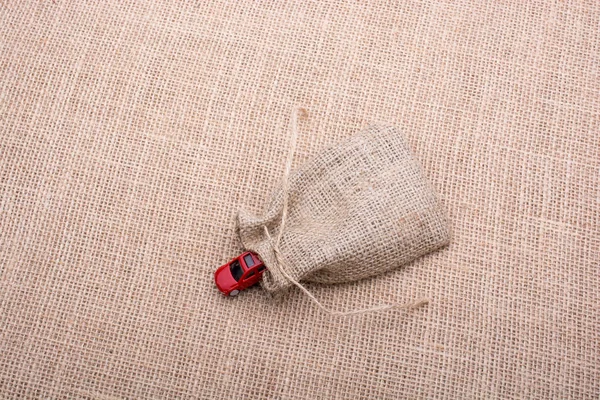Coche de juguete rojo de un saco de lino sobre un lienzo —  Fotos de Stock