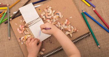 Spiral defter üzerinde bir renk kalem tutan el 