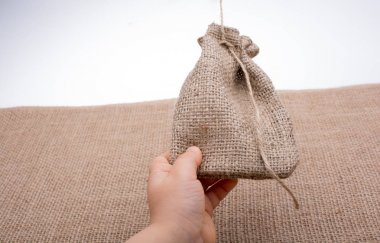 Çarşaftan yapılmış boş bir çuvalı tutan el.
