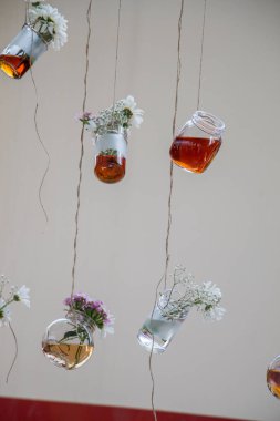 İplere asılı çiçekli bitkisel çay şişeleri