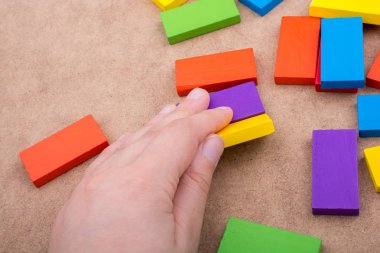 Çeşitli renklerin ahşap bloklarından birini tutarken