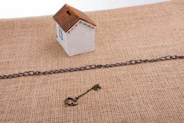 Retro anahtar ve tuvalin üzerindeki zincirin ötesinde bir model ev.