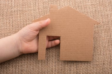 Tuvalin arka planında bir bez evi tutan el.