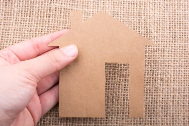 Tuvalin arka planında bir bez evi tutan el.