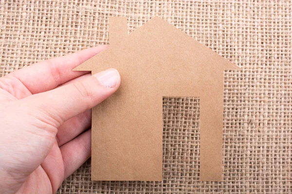 Tuvalin arka planında bir bez evi tutan el.