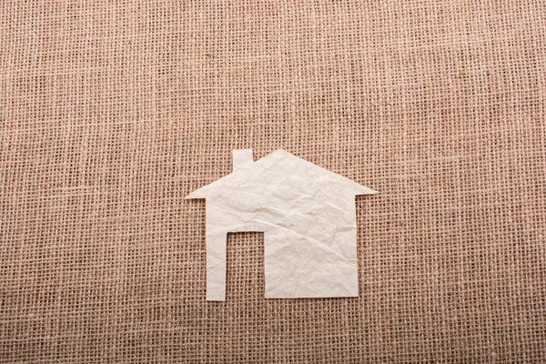 Tuvalin arka planında kağıttan yapılmış küçük bir ev şekli.