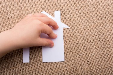 Tuvalin arka planında bir bez evi tutan el.