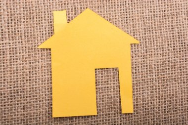 Tuvalin arka planında kağıttan yapılmış küçük bir ev şekli.