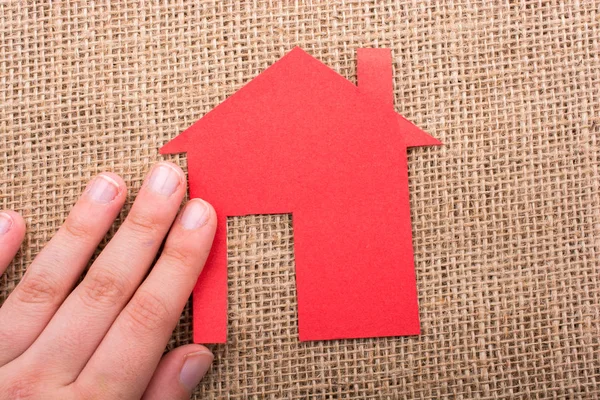 Tuvalin arka planında bir bez evi tutan el.