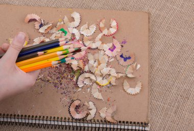 Bir defter kalem talaş ile üzerinde renkli kalemler tutan el