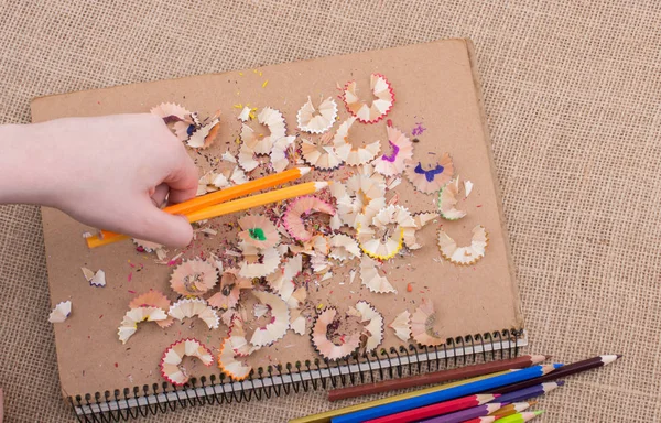 Renkli kalemler üzerinde bir defter tutan el